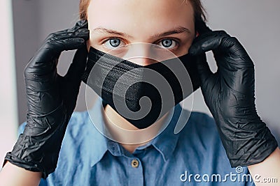 A nurse dressing a black mask and medical gloves and looking in the camera and thinks how to protect people from the coronavirus. Stock Photo
