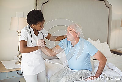 Nurse examining a senior man on bed in bedroom Stock Photo