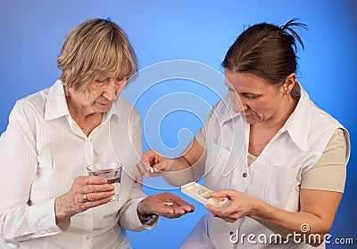 Nurse is helping elderly woman with handing out pills Stock Photo