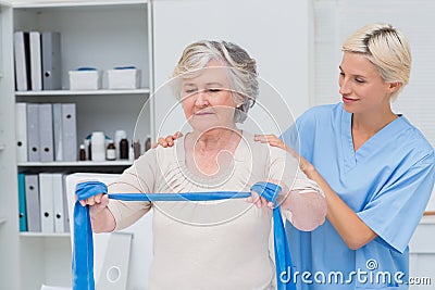 Nurse helping senior patient in exercising with resistance band Stock Photo