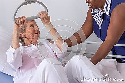 Nurse helps a patient to get up in hospital :nurse helping senior woman get up with credence Editorial Stock Photo