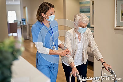 Nurse helping senior woman walk at nursing home Stock Photo