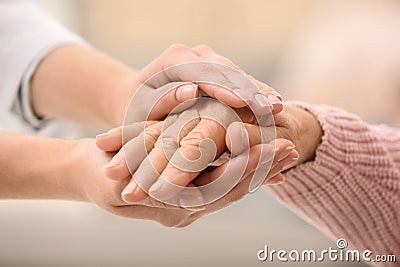 Nurse holding hands of elderly woman against blurred background. Assisting senior generation Stock Photo