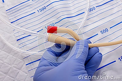 Nurse inflates urinary catheter bulb with leg drainage bag on sterile field. Stock Photo