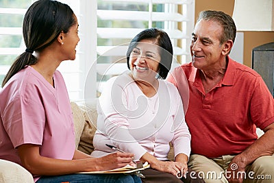 Nurse Making Notes During Home Visit With Senior Couple Stock Photo