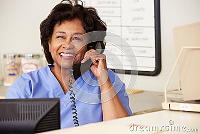 Nurse Making Phone Call At Nurses Station Stock Photo