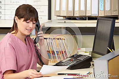 Nurse Making Phone Call At Nurses Station Stock Photo