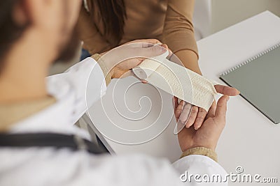 Nurse at medical office providing first aid applying bandage on patient's sprained wrist Stock Photo