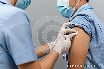 Nurse or Medical professionals holding syringe and using cotton before make injection to dortor in mask. Covid-19 or coronavirus Stock Photo