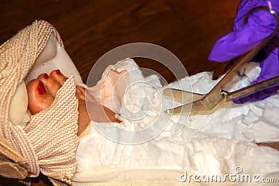 A nurse with purple plastic gloves cuts a cast bandage off of an ankle with foot and toes showing - selective focus Stock Photo