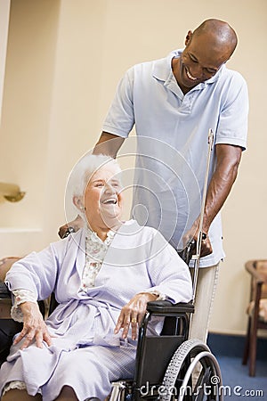 Nurse Pushing Senior Woman In Wheelchair Stock Photo