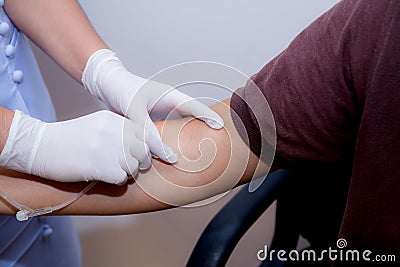 Nurse putting an IV needle into a patients hand. Stock Photo