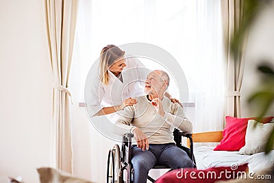 Nurse and senior man in wheelchair during home visit. Stock Photo