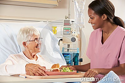 Nurse Serving Senior Female Patient Meal In Hospital Bed Stock Photo
