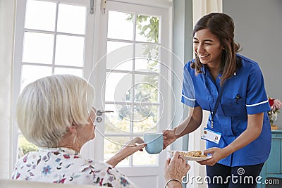 Nurse serving tea to senior woman at home, close up Stock Photo