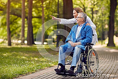 Nurse showing something to elderly man on wheelchair Stock Photo