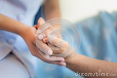 Nurse sitting on a hospital bed next to an older woman helping hands, care for the elderly concept Stock Photo