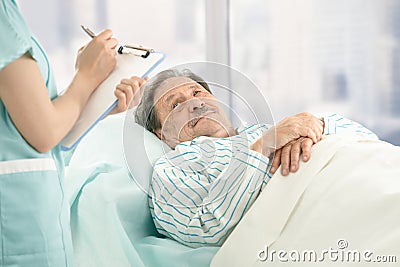 Nurse taking notes of old patient Stock Photo