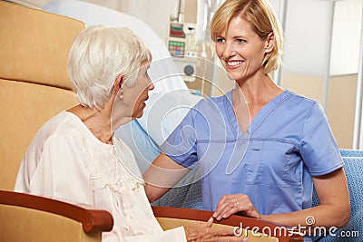 Nurse Taking To Senior Female Patient Seated In Chair Stock Photo