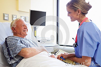 Nurse Talking To Senior Male Patient In Hospital Room Stock Photo