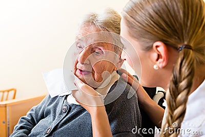 Nurse wiping mouth of senior woman in nursing home Stock Photo