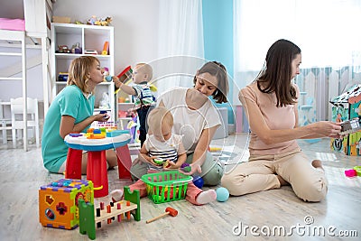 Nursery babies play together with moms in creche or children club Stock Photo