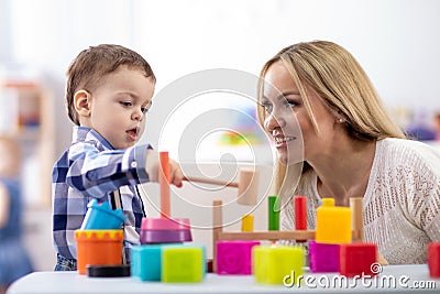 Nursery baby and caregiver play with montessori toys at table in daycare centre Stock Photo