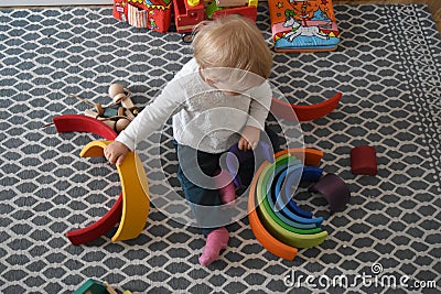 Nursery school - baby playing with wood rainbow Editorial Stock Photo