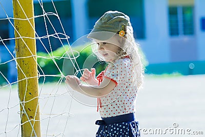 Nursery school girl playing near football goal net with yellow goalposts Stock Photo