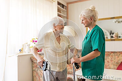 Nursing assistant helping senior woman with walking frame Stock Photo