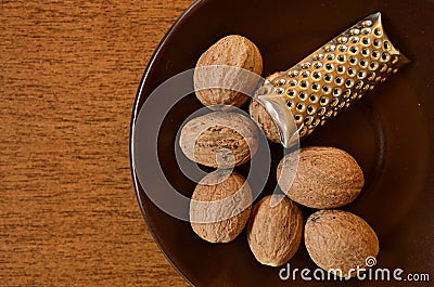 Nutmeg on a saucer with a nut grater. Stock Photo