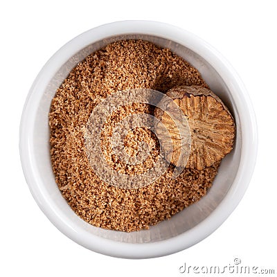Nutmeg seed and ground nutmeg isolated on white. Freshly grated spice in white bowl. Close-up, top view Stock Photo