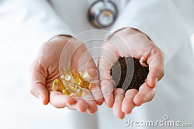 Nutritionist holding omega pills in one hand and dry tea in the other hand over white background. Stock Photo