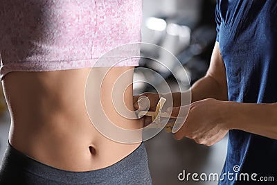 Nutritionist measuring woman`s body fat layer with caliper, closeup Stock Photo