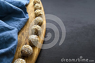 nutritious energy balls consisting of nuts, oatmeal, honey, dried fruits on a wooden board on a black slate background Stock Photo