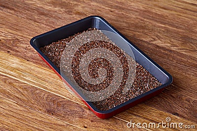 Nutritious flaxseed on baking tray over wooden background, selective focus, shallow depth of field. Stock Photo