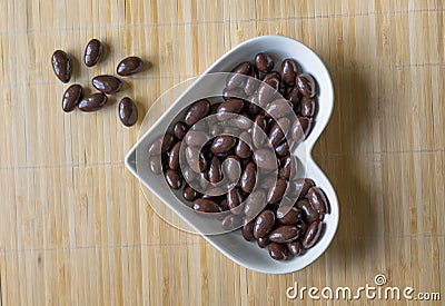 Nuts arranged in heart shape on background. Food image close up candy, chocolate milk, extra dark almond nuts. Love Texture Stock Photo