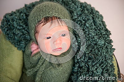 Nwborn swaddled in green coccon lying on basket Stock Photo