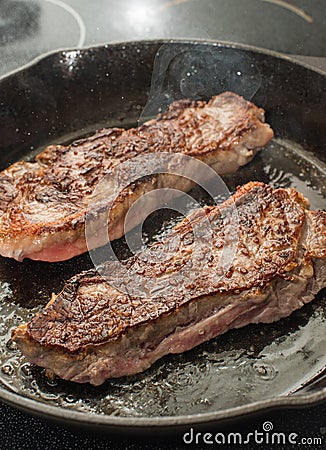 New York Strip Steaks in iron skillet Stock Photo