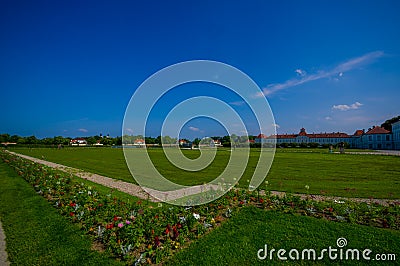 Nymphenburg, Germany - July 30, 2015: Very big grass field bathing with sunshine, some buildings in background, palace Editorial Stock Photo