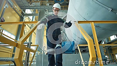 O coordenador no capacete de segurança está andando na fábrica da indústria pesada O coordenador no capacete de segurança está andando na fábrica da indústria pesada