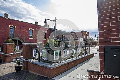 O`neal Plaza with red brick buildings, black metal fences, bare winter trees and lush green plants along Veterans Memorial Hwy Editorial Stock Photo
