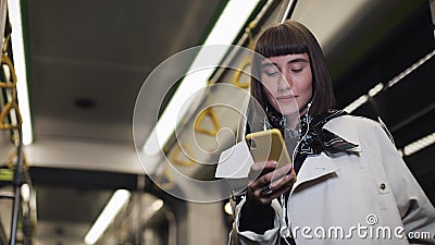 O retrato da jovem mulher bonita nos fones de ouvido que montam em público o transporte, escuta música e consultando no amarelo video estoque O retrato da jovem mulher bonita nos fones de ouvido que montam em público o transporte, escuta música e consultando no amarelo video estoque