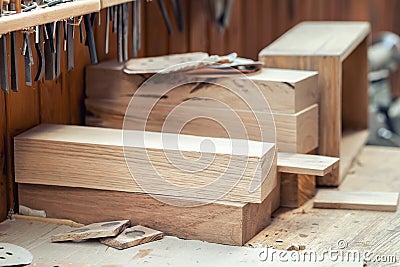Oak wooden bar blocks materials stacked at carpentry woodwork workshop with tools and sawdust on background. Timber wood blanks at Stock Photo