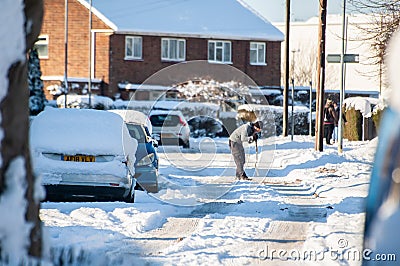 OAKHAM, RUTLAND, ENGLAND- 25 JANUARY 2021: Man shovelling snow in Oakham Editorial Stock Photo