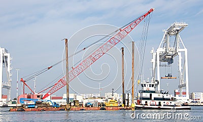Tugboat pushing barge with heavy equipment past the Port of Oakland Editorial Stock Photo