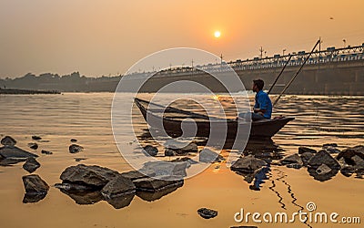 Oarsman sits on his boat to shore at sunset on river Damodar near the Durgapur Barrage. Editorial Stock Photo