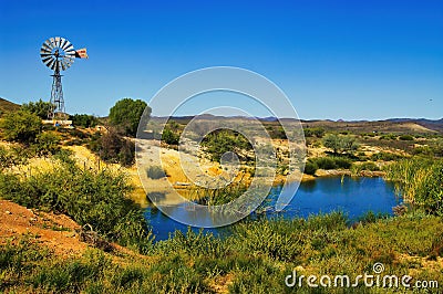 Oasis with windmill and small lake in the South Australian desert Stock Photo