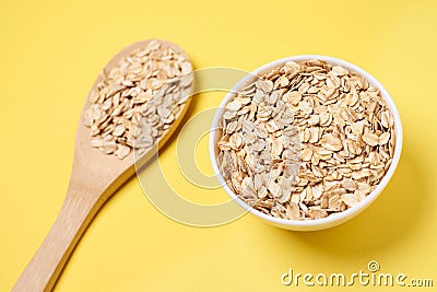 Oat flakes. Healthy eating. Wooden spoon. Yellow background Stock Photo