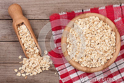 Oat flakes in a wooden bowl with a scoop on old wooden background Stock Photo